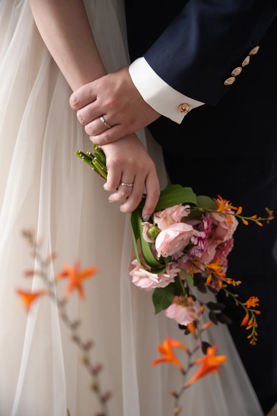 Đôi tay đeo nhẫn cùng bó hoa cưới